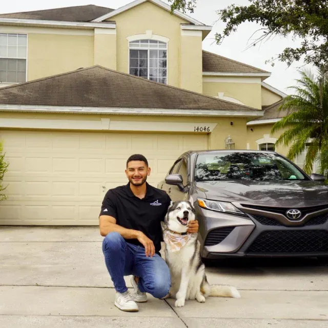 Offer Charm team member kneeling with a husky in front of a Florida home